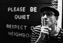 Please be quiet written on a wall with a male making a shh motion with hands